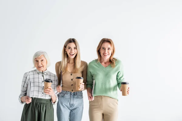 Tre generazioni di donne eccitate che tengono giornali e bicchieri di carta isolati su bianco — Foto stock
