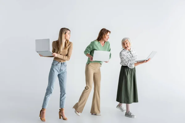 Full length of three generation of women with laptops on white — Stock Photo