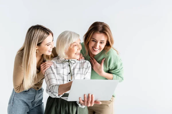 Drei Generationen glücklicher Frauen, die vereinzelt auf weißen Laptop schauen — Stockfoto