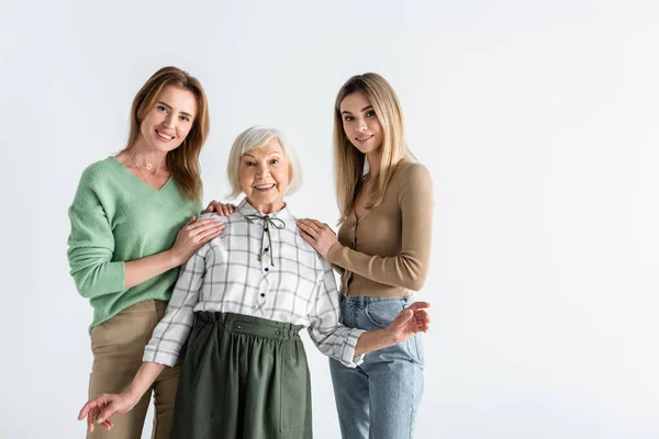 Tres generaciones de mujeres complacidas mirando a la cámara aislada en blanco - foto de stock