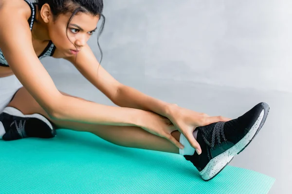 Young african american sportswoman doing stretching exercise on fitness mat at home — Stock Photo
