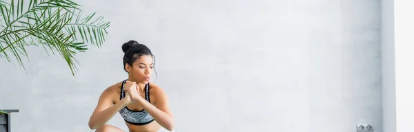 Young african american woman in sports bra warming up at home, banner — Stock Photo