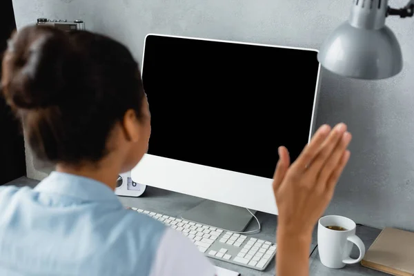 Back view of african american freelancer waving hand during video call, blurred foreground — Stock Photo