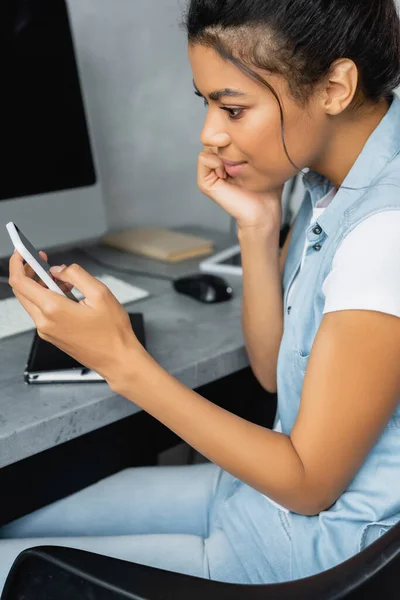 Seitenansicht der jungen afrikanisch-amerikanischen Freelancer Messaging auf dem Smartphone zu Hause — Stockfoto