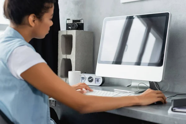 Jeune pigiste afro-américain travaillant sur un ordinateur portable à la maison, avant-plan flou — Photo de stock