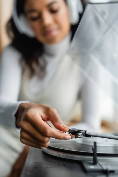 Foco seletivo da mulher africana americana em fones de ouvido sem fio ligando gravador, fundo embaçado — Fotografia de Stock