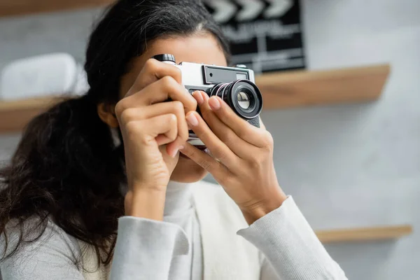 Young african american woman taking picture on vintage photo camera at home — Stock Photo