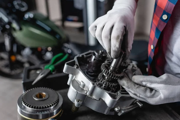 Partial view of technician in gloves examining disassembled motorbike gearbox — Stock Photo