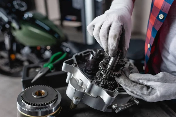 Teilansicht des Technikers in Handschuhen bei der Untersuchung des zerlegten Motorradgetriebes — Stockfoto