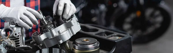 Ausgeschnittene Ansicht des Mechanikers in Handschuhen bei der Überprüfung des zerlegten Motorradgetriebes, Banner — Stockfoto