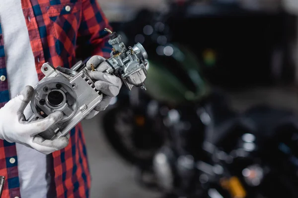 Обрізаний вид механіка в рукавичках, що тримає частину коробки передач мотоцикла — стокове фото