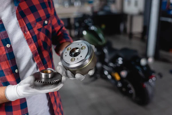 Cropped view of technician in gloves holding gearwheels of motorbike transmission — Stock Photo