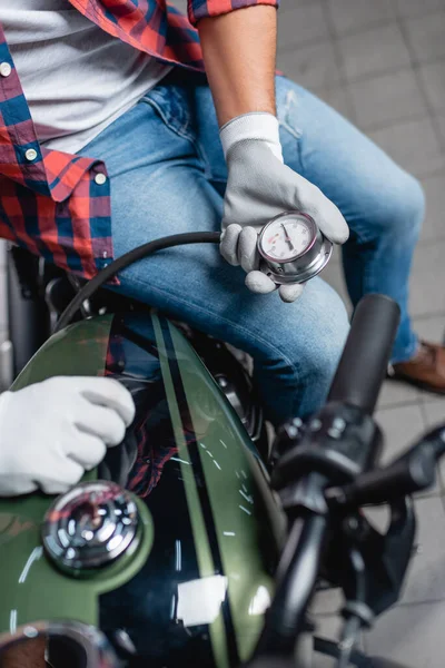 Selective focus of manometer in hands of technician measuring air pressure in tire of motorcycle — Stock Photo