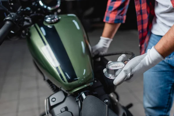 Teilansicht des Technikers mit Luftmessgerät während der Druckmessung im Reifen des Motorrads — Stock Photo