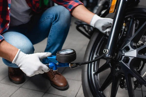 Ausgeschnittene Ansicht eines Technikers zur Messung des Luftdrucks im Reifen eines Motorrads mit Manometer, verschwommener Hintergrund — Stockfoto
