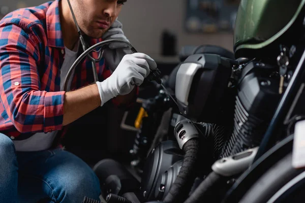 Ausgeschnittener Blick auf jungen Reparateur, der Motorrad-Motor mit Stethoskop untersucht — Stockfoto