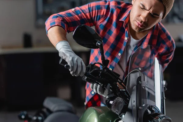 Jovem mecânico verificando punho do freio no guidão da motocicleta — Fotografia de Stock