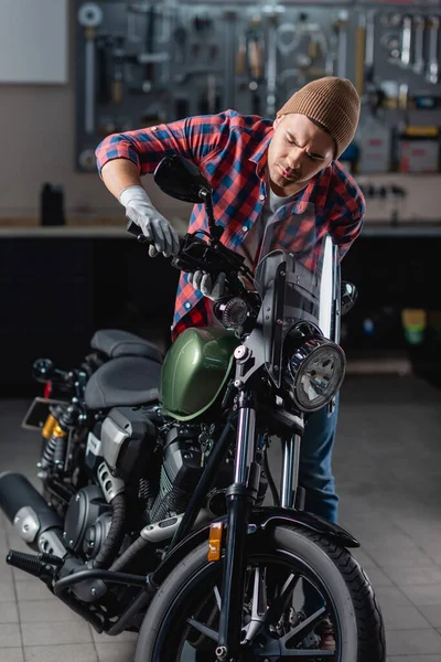 Mecânico em camisa quadriculada e luvas examinando alça de freio no guidão da motocicleta — Fotografia de Stock