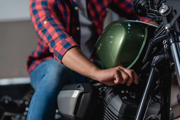 Cropped view of mechanic checking motorcycle in workshop, blurred background — Stock Photo