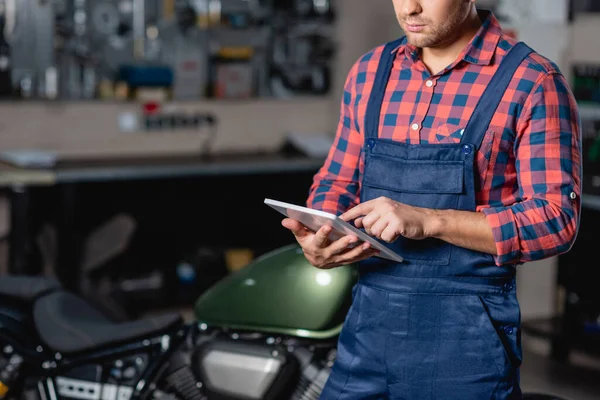 Cropped view of technician in overalls using digital tablet in workshop — Stock Photo