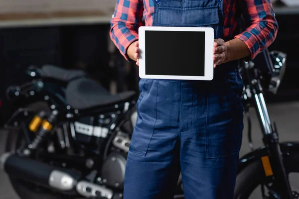 Vue partielle du mécanicien tenant tablette numérique avec écran blanc près de la moto sur fond flou — Photo de stock