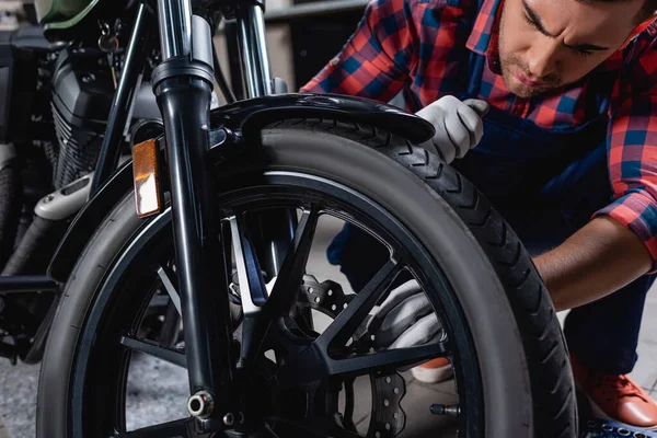 Junger Mechaniker überprüft Rad des Motorrads in Werkstatt — Stockfoto