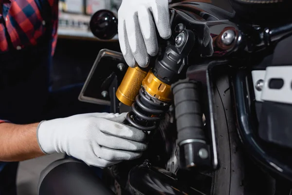 Cropped view of mechanic checking shock absorber of motorcycle in workshop — Stock Photo