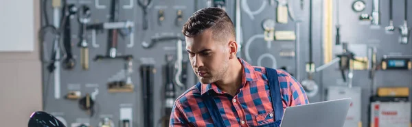 Young mechanic in plaid shirt working in garage, banner — Stock Photo