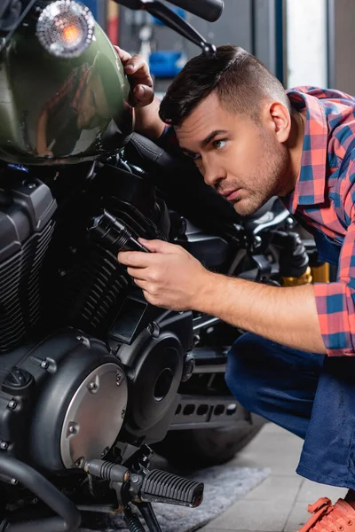Giovane meccanico in possesso di torcia elettrica durante l'esame moto — Foto stock