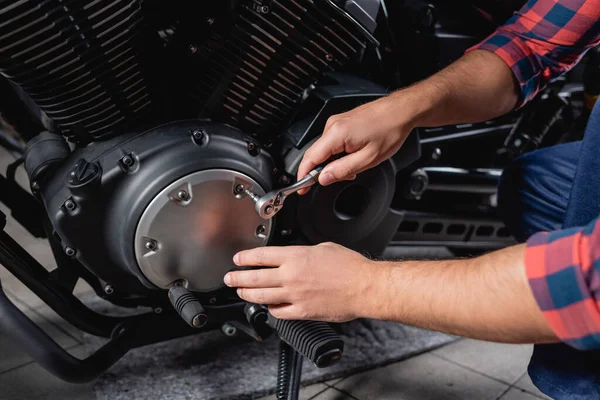 Partial view of mechanic unscrewing cap of motorbike gearbox with socket wrench — Stock Photo