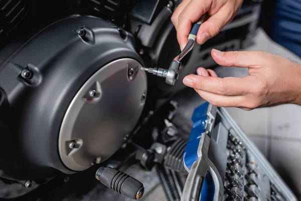 Cropped view of mechanic unscrewing cap of motorbike gearbox with socket wrench — Stock Photo