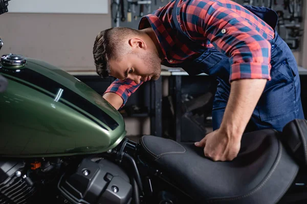 Repairman in overalls making diagnostics of motorbike in workshop — Stock Photo