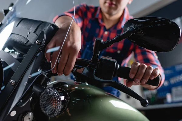 Cropped view of mechanic checking brake handle of motorcycle on blurred background — Stock Photo