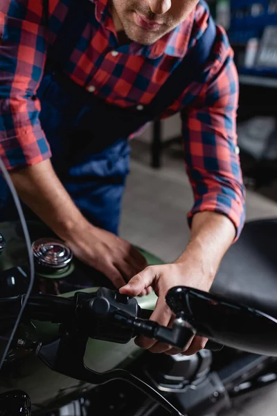 Cropped view of mechanic checking start button on motorcycle handlebar, blurred foreground — Stock Photo