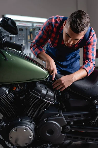 Junger Mechaniker zeigt mit dem Finger, während er in der Werkstatt die Diagnose des Motorrads stellt — Stockfoto