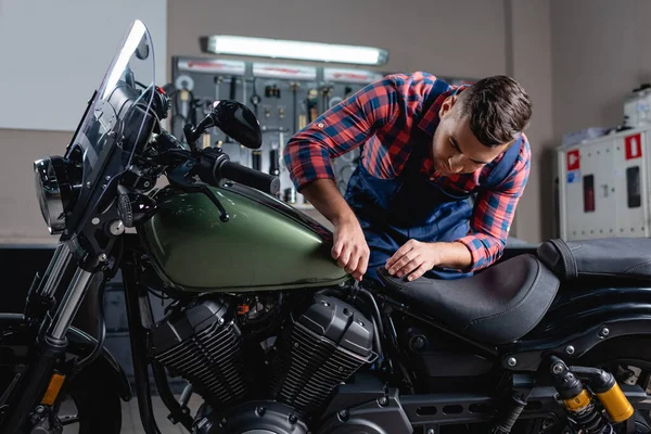 Reparador en overol haciendo diagnosticos de moto en taller - foto de stock