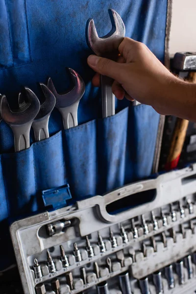 Ausgeschnittene Ansicht des Mechanikers, der Schraubenschlüssel vom Set in der Nähe des Werkzeugkastens nimmt — Stockfoto