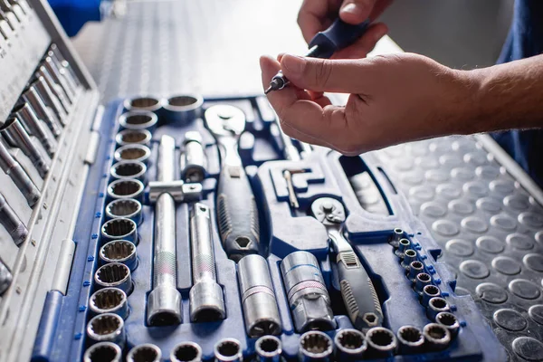 Cropped view of mechanic holding screwdriver near toolbox in workshop — Stock Photo