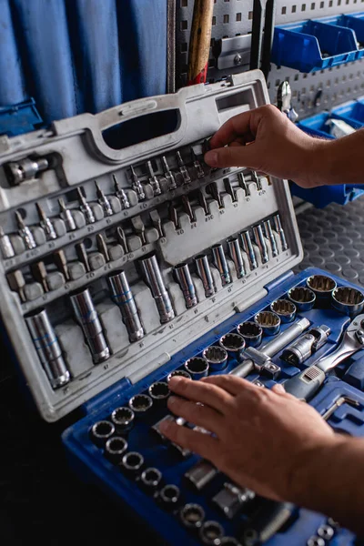 Cropped view of mechanic choosing instrument in toolbox, blurred foreground — Stock Photo