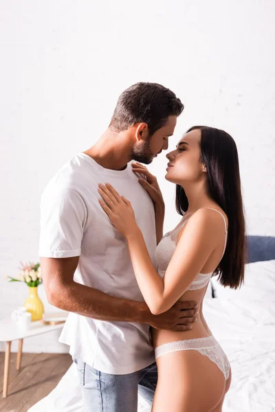 Sexy young couple hugging and looking at each other in bedroom — Stock Photo