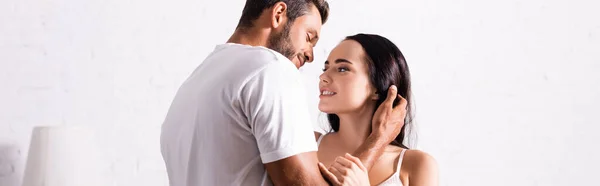 Apasionado hombre joven en camiseta mirando a la mujer morena en el interior, pancarta - foto de stock