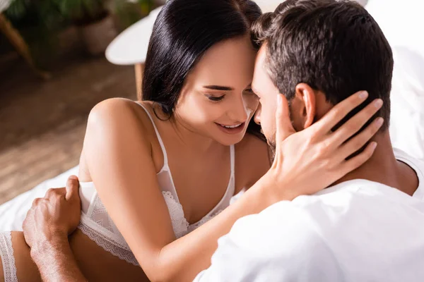 Sensual brunette woman in lingerie hugging man indoors on blurred background — Stock Photo