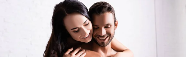 Sorrindo morena mulher abraçando o homem sem camisa dentro de casa, banner — Fotografia de Stock