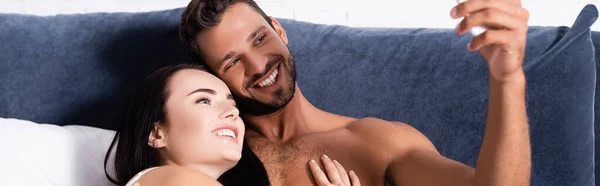 Happy young couple taking selfie on bed, banner — Stock Photo