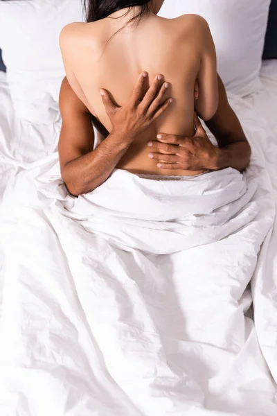 Abgeschnittene Ansicht eines jungen Mannes, der Freundin auf dem Bett umarmt — Stockfoto