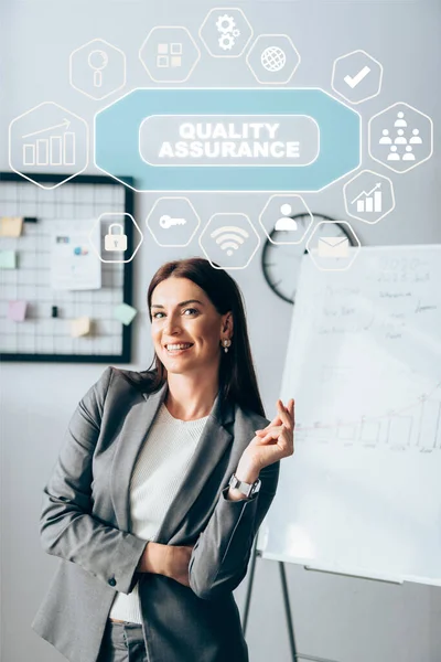 Positive investor looking at camera near symbols and quality assurance illustration on office — Stock Photo
