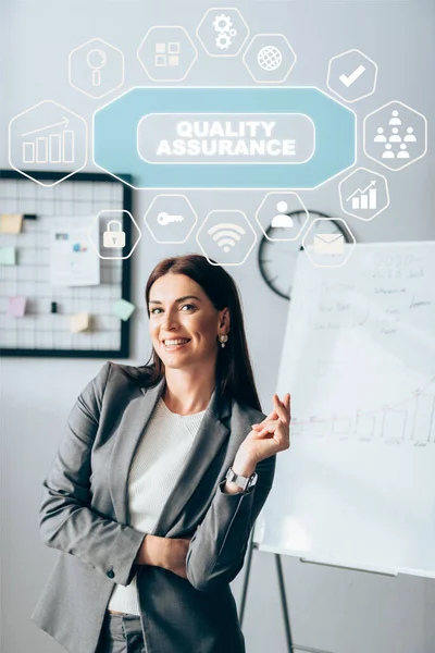 Positiver Investor blickt auf Kamera in der Nähe von Symbolen und Qualitätssicherung im Büro — Stockfoto