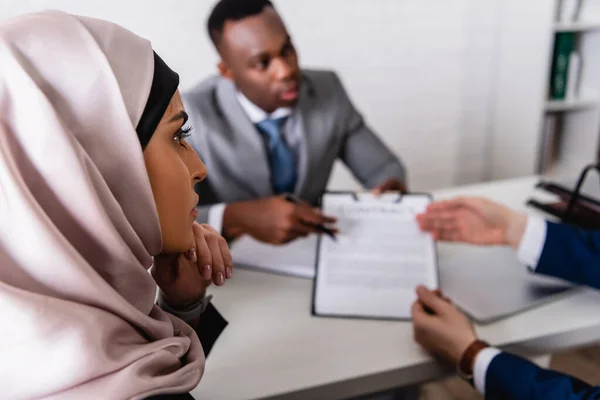 Arabische Geschäftsfrau in der Nähe multikultureller Geschäftspartner diskutiert Vertrag auf verschwommenem Hintergrund — Stockfoto