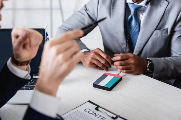 Vue recadrée du traducteur pointant avec stylo près d'un homme d'affaires afro-américain au premier plan flou — Photo de stock