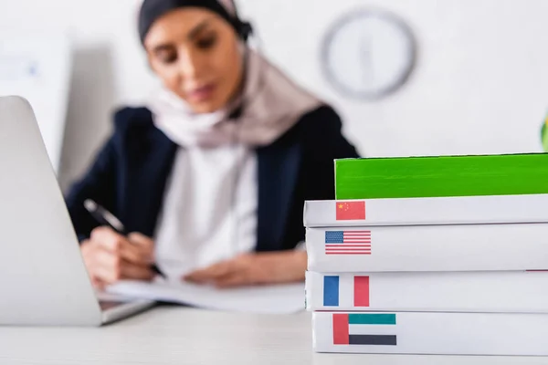 Foyer sélectif des dictionnaires de langues étrangères près traducteur arabe travaillant sur fond flou — Photo de stock